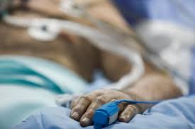 A person laying in bed with an iv hanging from the side of their arm.